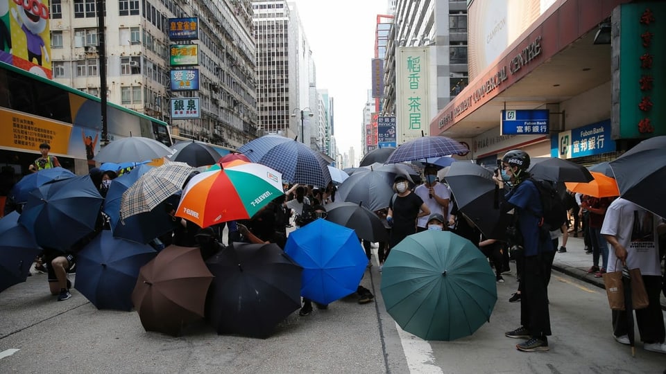 Protestierende mit farbigen Schirmen.