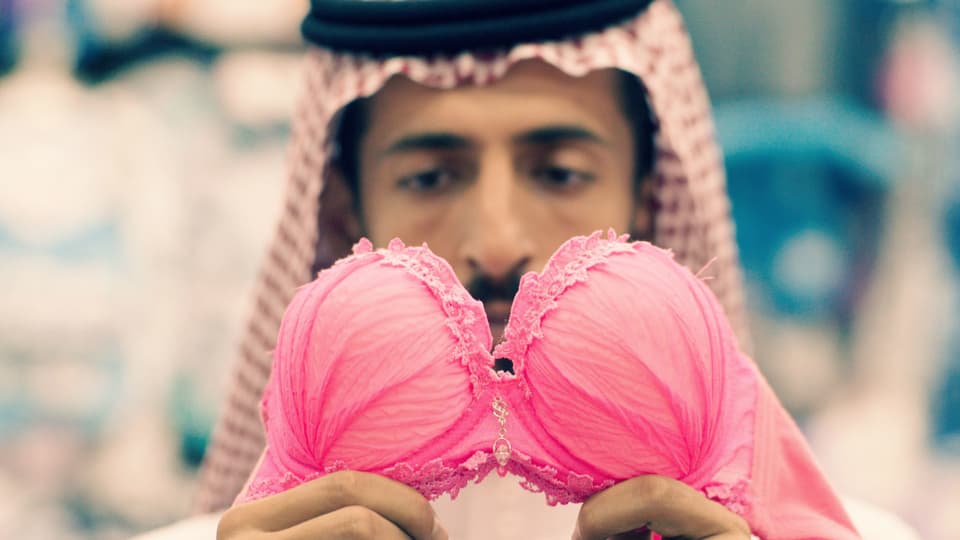 Mann in saudischer Kleidung hätl BH hoch.