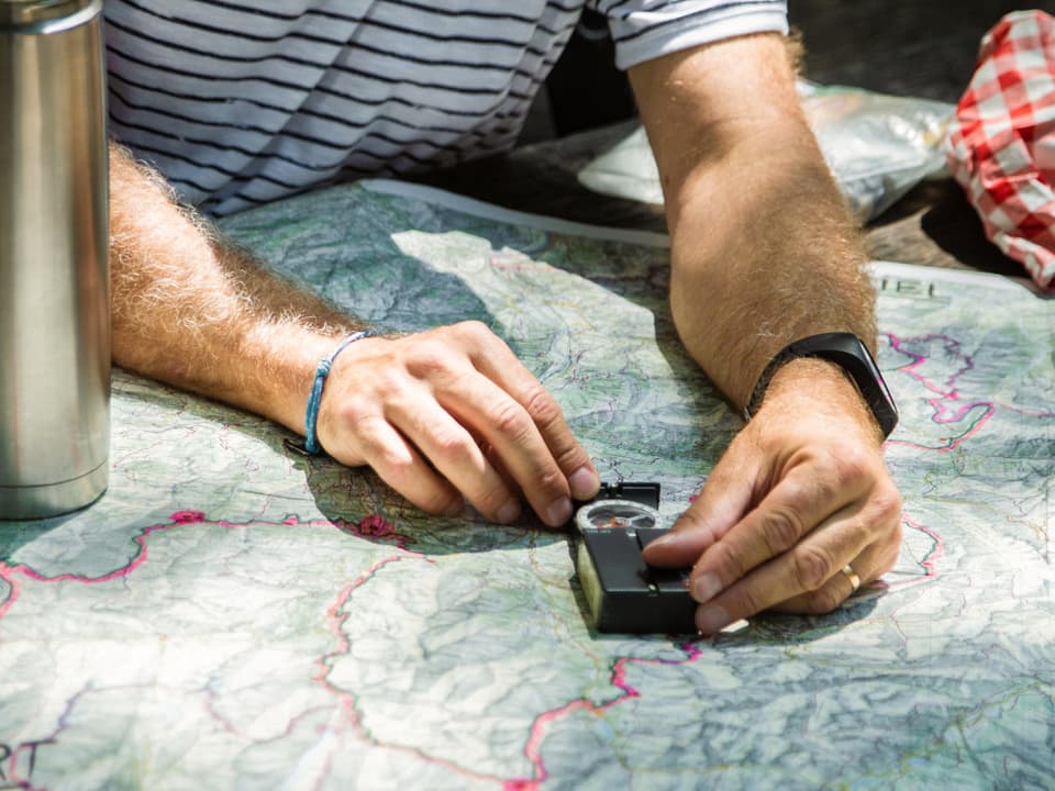 SRF 1-Outdoor-Reporter Marcel Hähni legt einen Kompass auf die Wanderkarte.