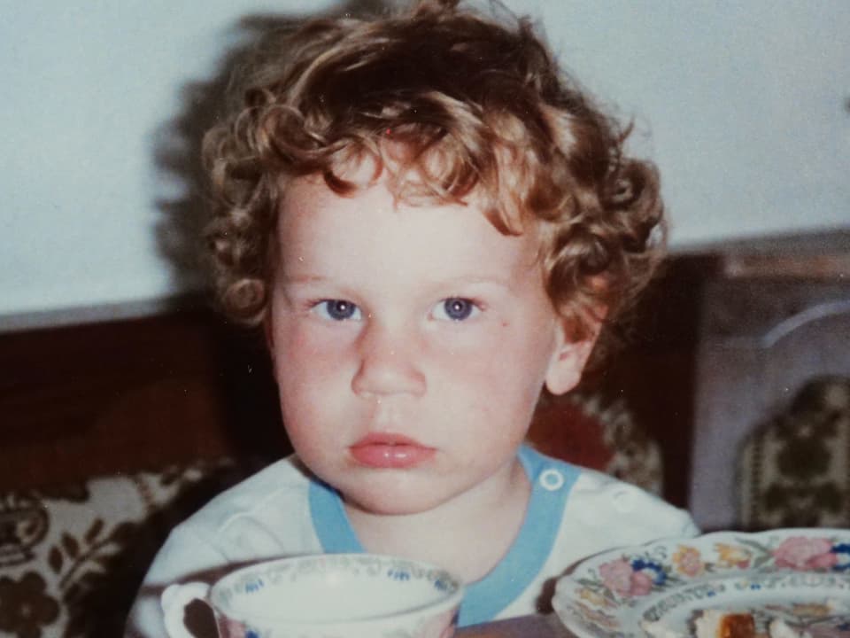 Christian Stucki als kleines Kind, mit blonden Locken, vor sich eine Schale und ein Teller