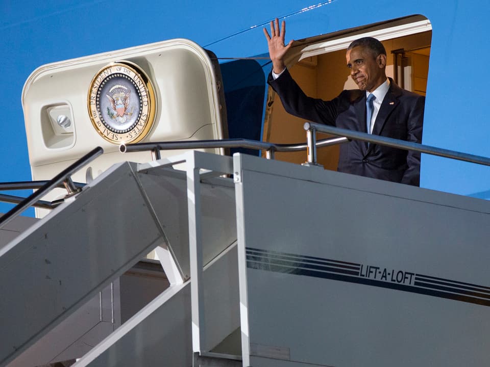 Barack Obama grüsst vor der Ture der Air Force One. 