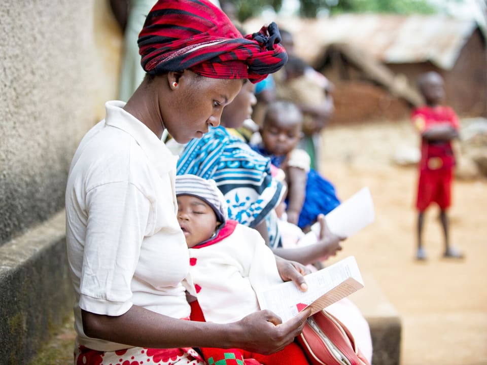 Frauen mit ihren Babys im Arm lesen eine Broschüre.