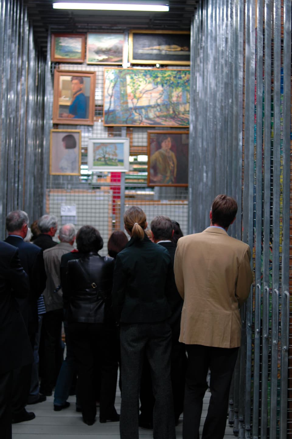 Ein Dutzend Menschen betrachtet Bilder an einer herausgezogenen Gitterwand im Archiv des Kunstmuseum Bern.