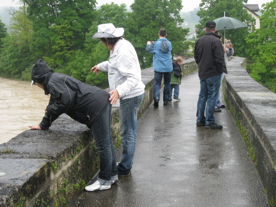 Menschen auf einer Brücke begutachten das Hochwasser der Thur.