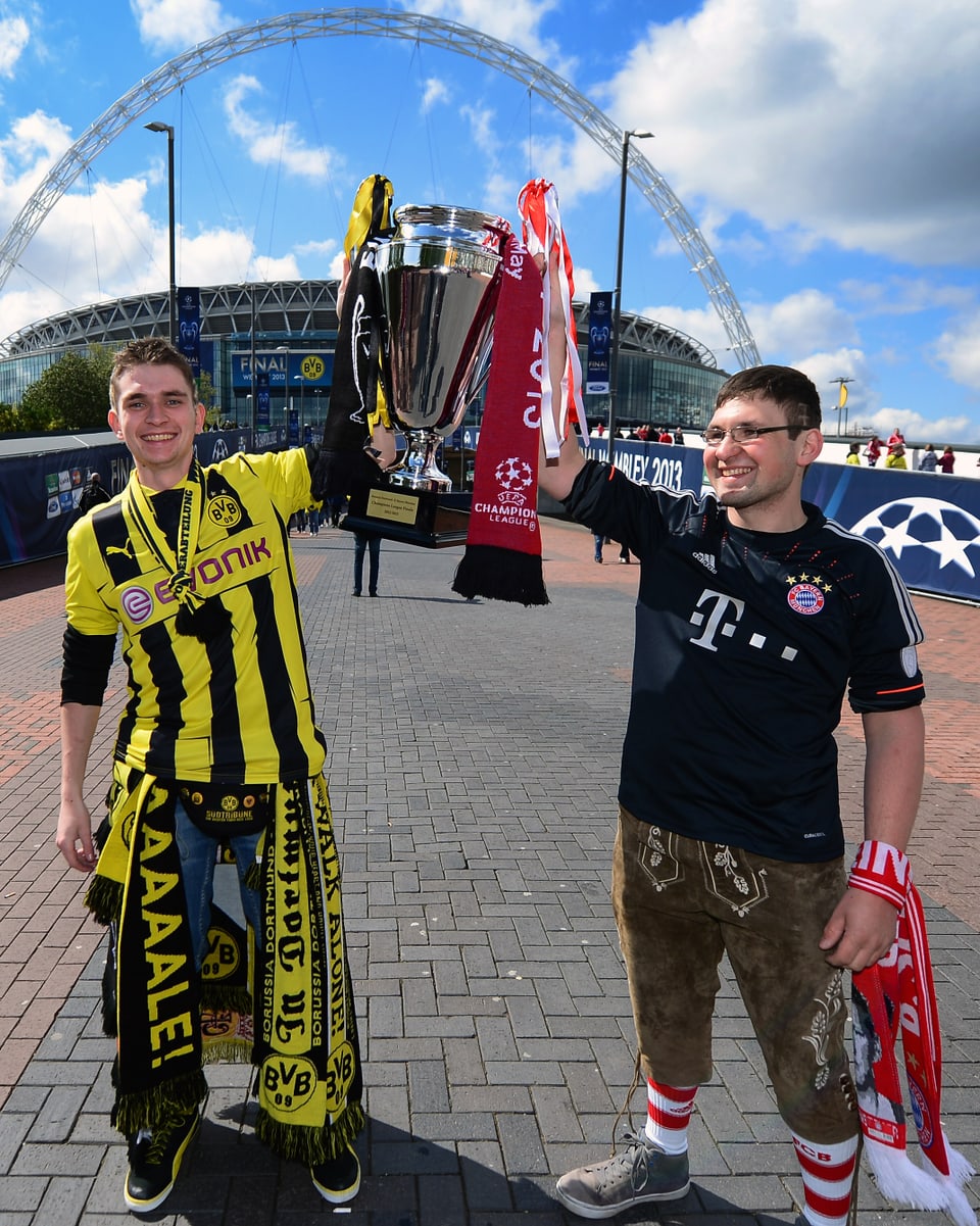 Ein BVB- und ein Bayern-Fan mit einem Replikt des Champions-League-Pokals.
