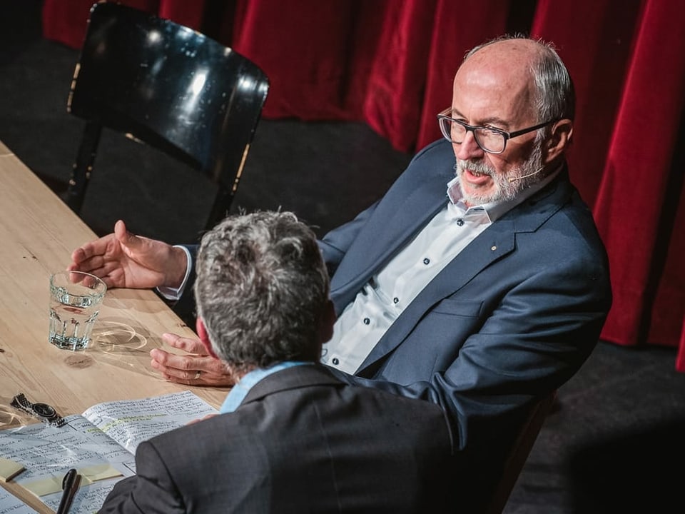 Unternehmer Willy Michel sitzt am Tisch und diskutiert mit Peter Brandenberger