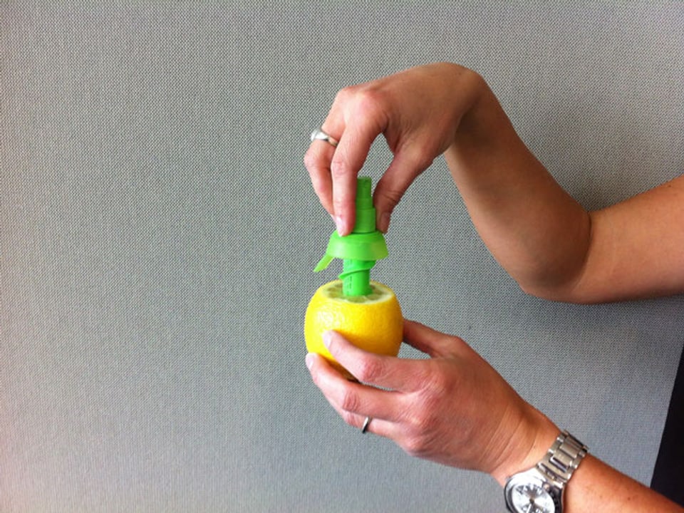 Der Sprühkopf wird in die Zitrone gedrückt.