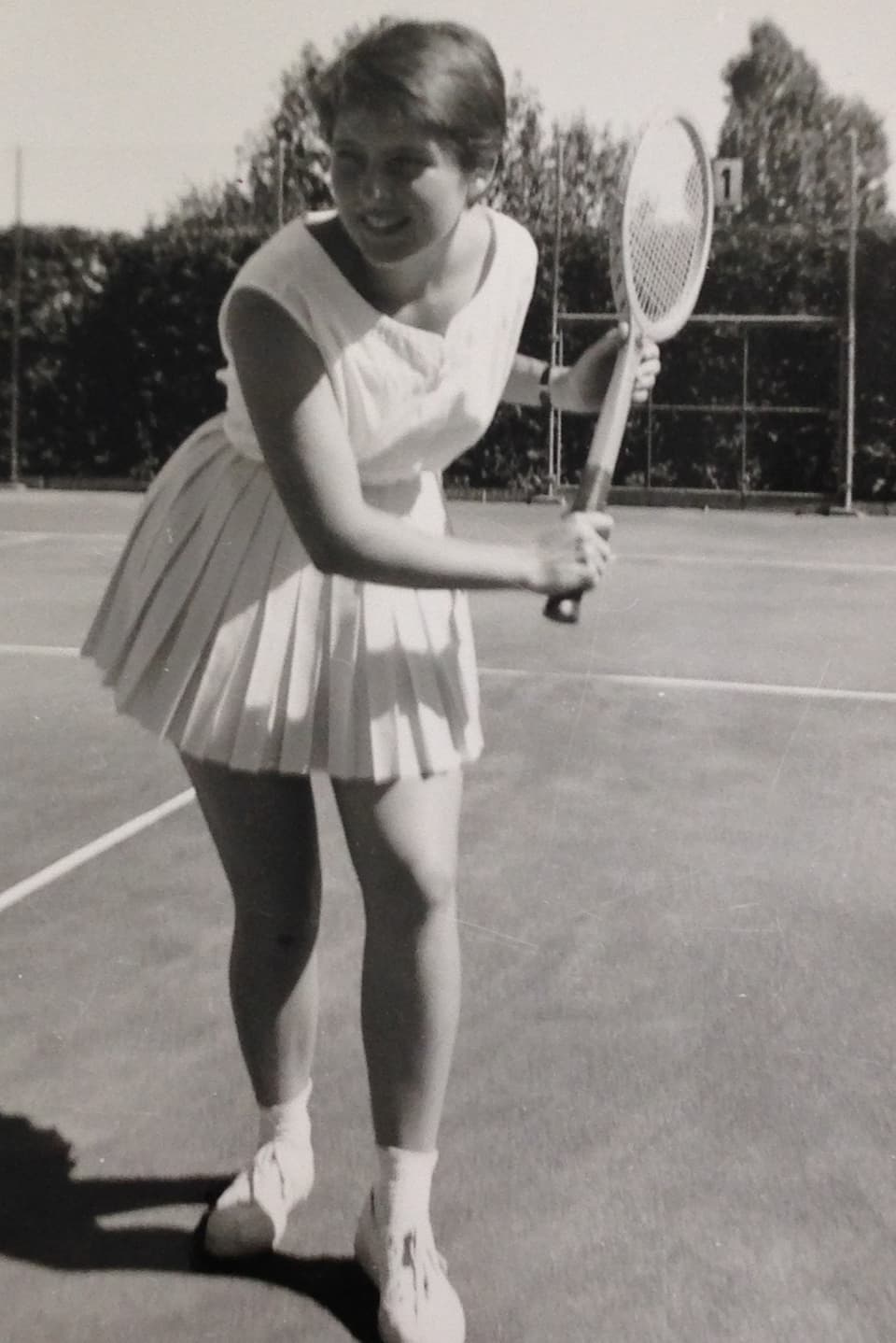 Eine junge Frau schwingt das Racket auf dem Tennisplatz.
