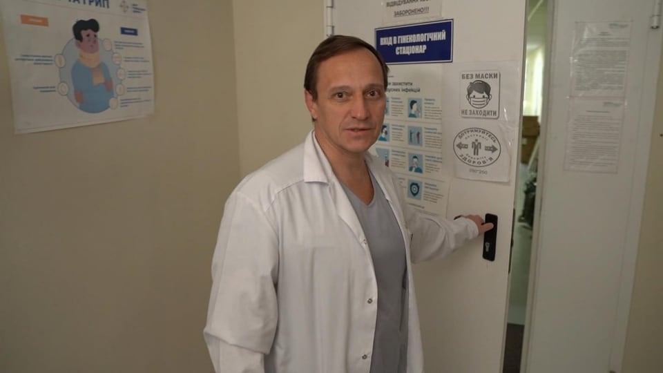 Arzt in weissem Kittel öffnet Türe zur Geburtenabteilung des Spitals von Ochtyrka.