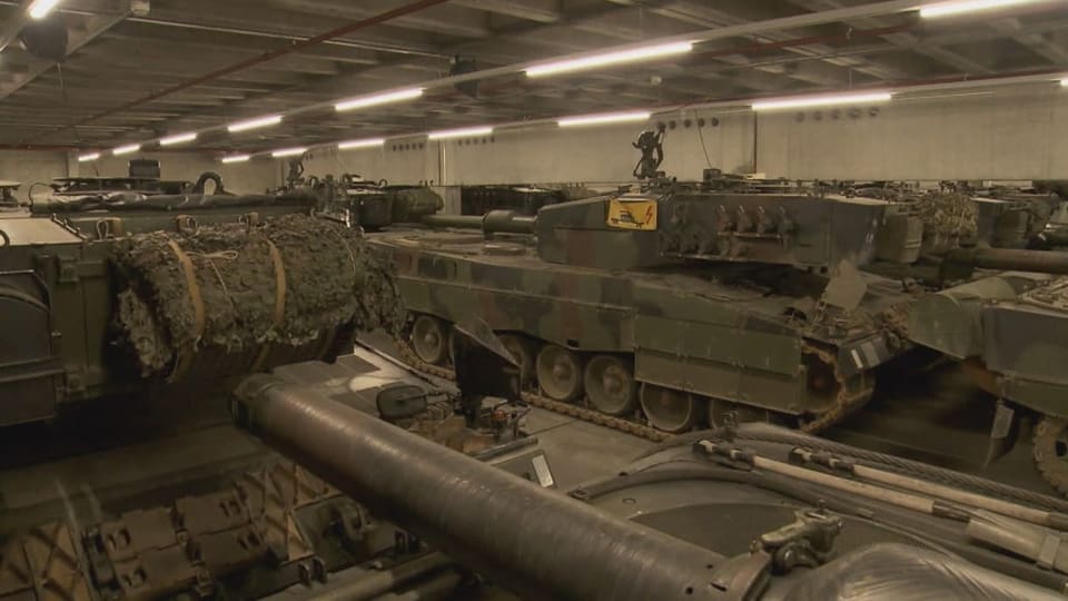 Eingemottete Kampfpanzer des Typs Leopard-2, etwa 20 sichtbar, stehen in einer Lagerhalle.