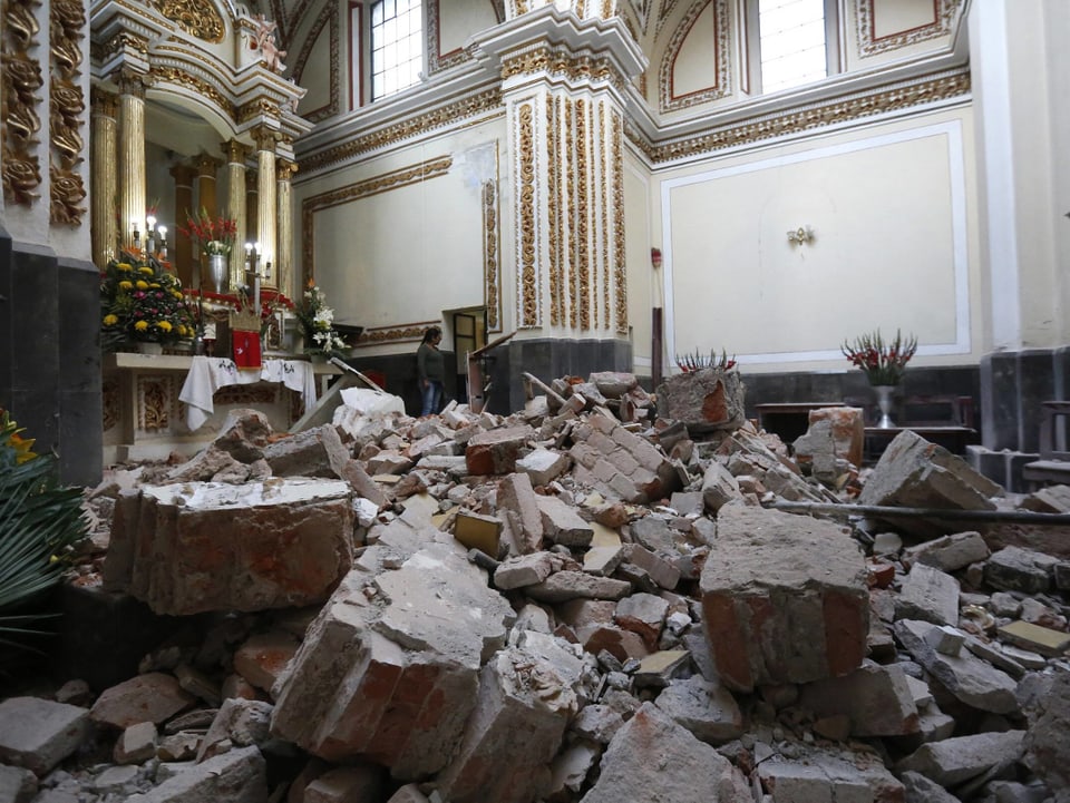 Trümmer im Innern einer Kirche, im Hintergrund der Altar.