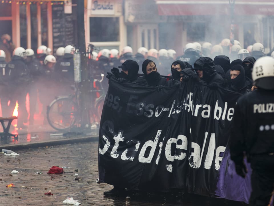 Vermummte Demonstranten mit einem Banner