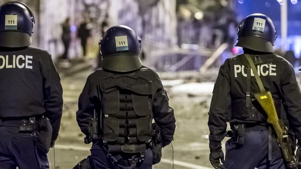 Polizisten in Schutzausrüstung von hinten bei Nacht