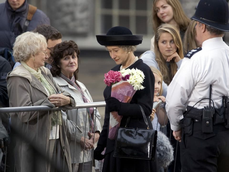 Frau mit Hut und Blumen inmitten von anderen Personen