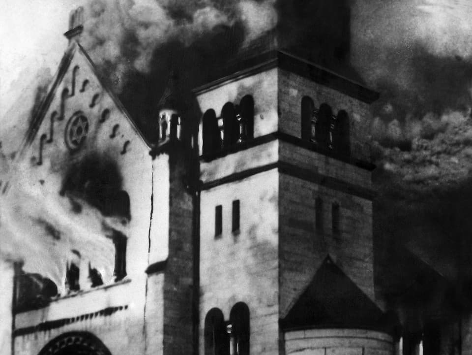 Schwarz-weisses Bild. Eine Synagoge steht in Flammen.