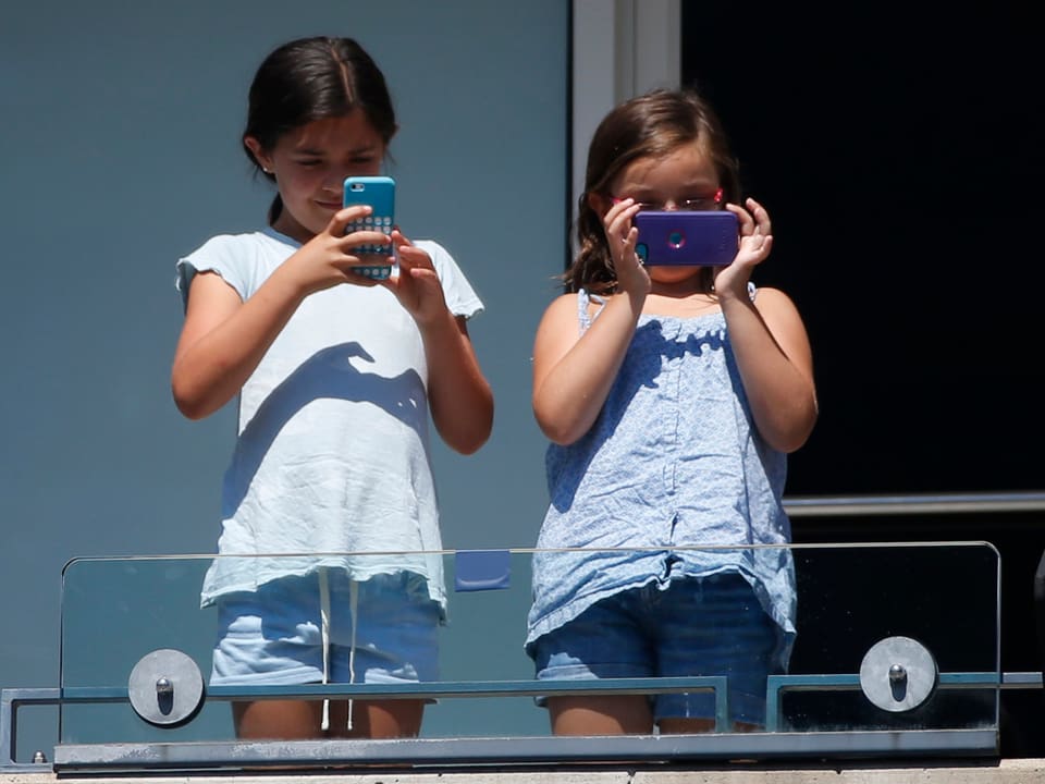 Zwei junge Mädchen mit Handys auf der Tribüne