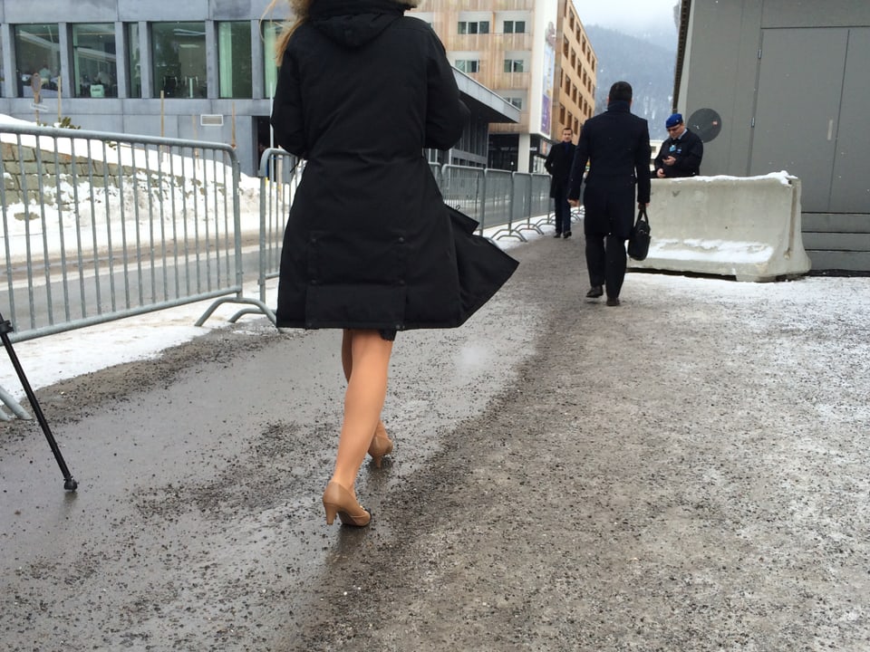 Frau geht Stöckelschuhen auf Strasse mit Schneeresten
