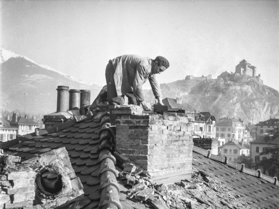 Ein Mann kniet auf einem zerstörten Hausdach in Sion.