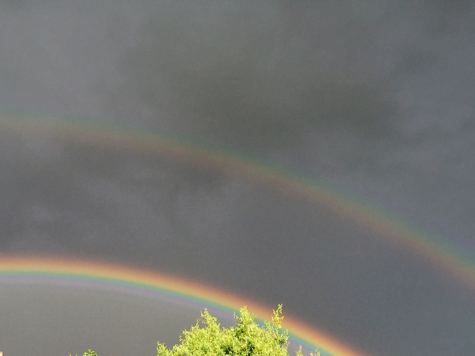 Dunkler Himmel mit Regenbogen und Doppelregenbogen dazu. 