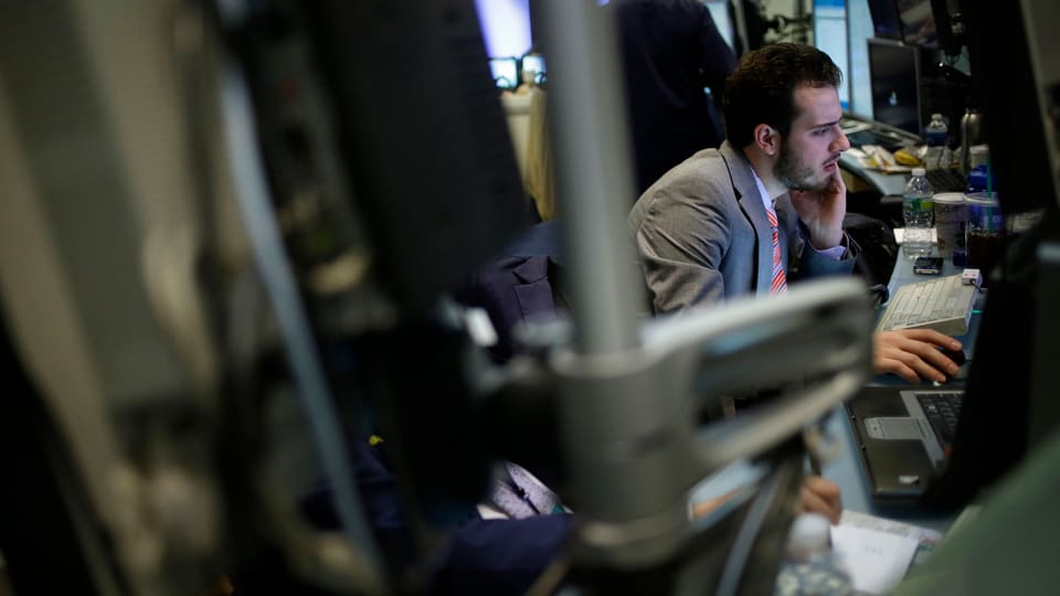 Ein junger Banker verschanzt sich hinter Computern an der Wall Street.