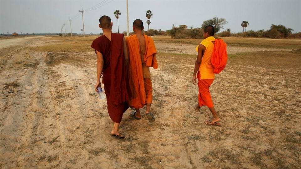 Buddhistische Mönche schreiten im kambodschanischen Dorf Trapang Chhouk durch ein vertrocknetes Feld.