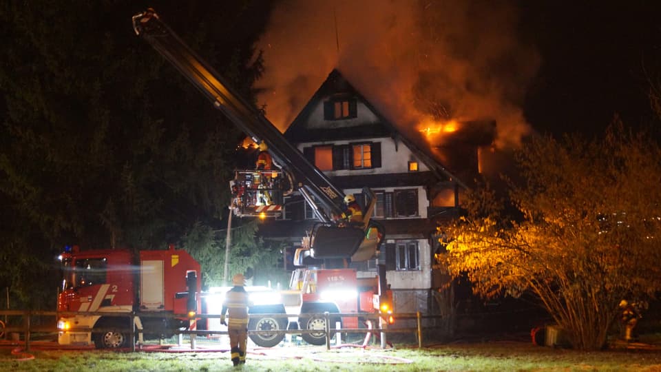 Feuerwehrleute löschen in Zug ein Holzhaus, das in Vollbrand steht.
