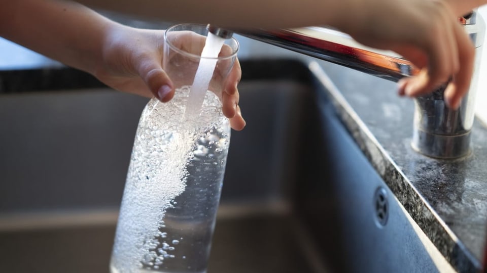 Person füllt Leitungswasser in eine Flasche.