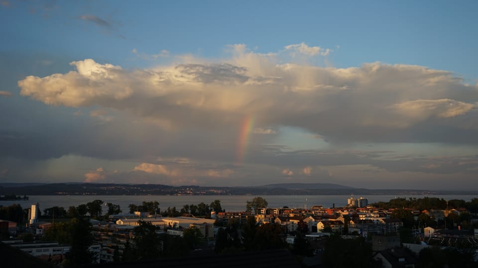 Blick von Kreuzlingen über den Bodensee mit Quellwolken und Regenbogen.