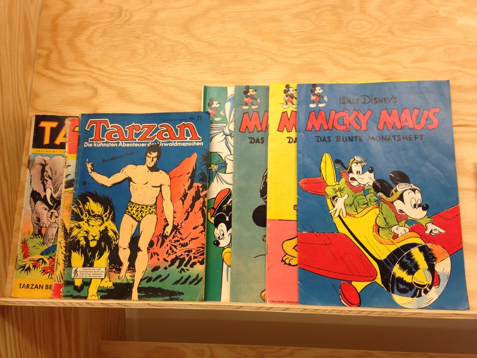 drei Micky Mouse Hefte liegen in einem Regal, daneben noch ein Tarzan Heft