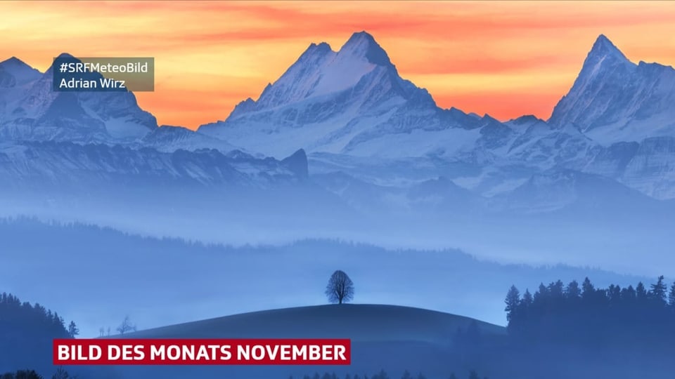 Blick auf Schneeberge im Dunst mit rot bis gelbem Himmel.