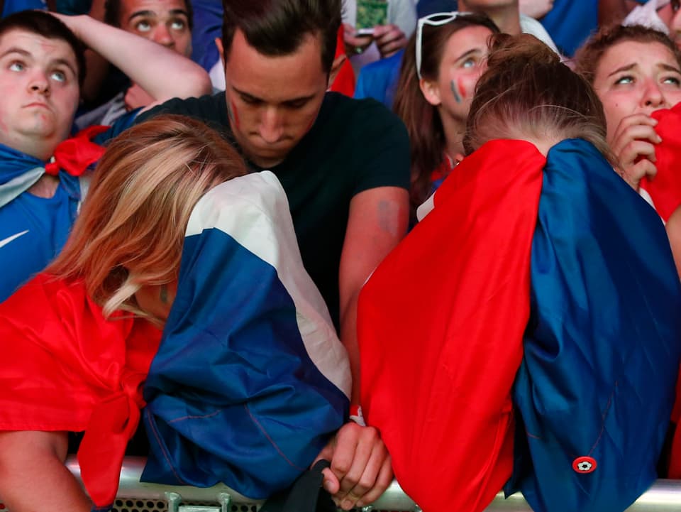 Französische Fans verbergen ihr Gesicht in der Staatsflagge
