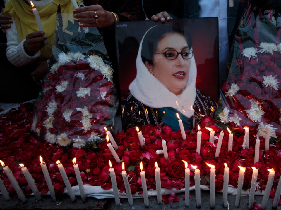 Portrait der ermordeten Benazir Bhutto umringt von Kerzen und Blumen.