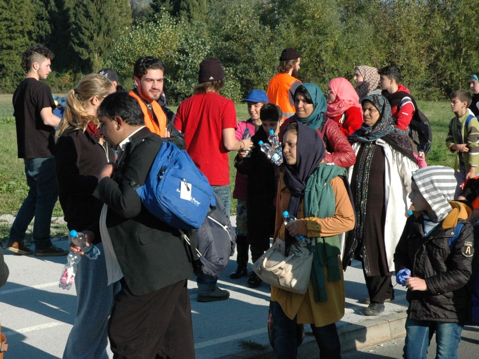 Die Helfer verteilen Trinkflaschen an den Strom von Flüchtlingen.