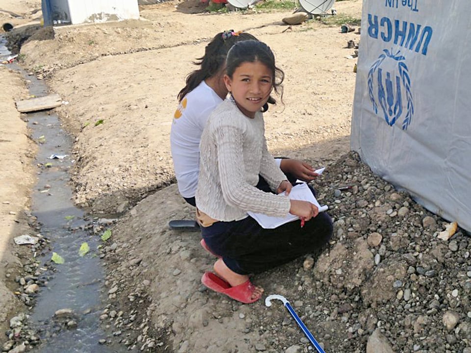 Zwei Mädchen kauern am Boden im Flüchtlingslager im Nordirak.