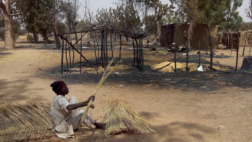 Ein Mann flechtet ein neues Dach für ein durch einen Bombenanschlag der Boko Haram beschädigtes Haus.