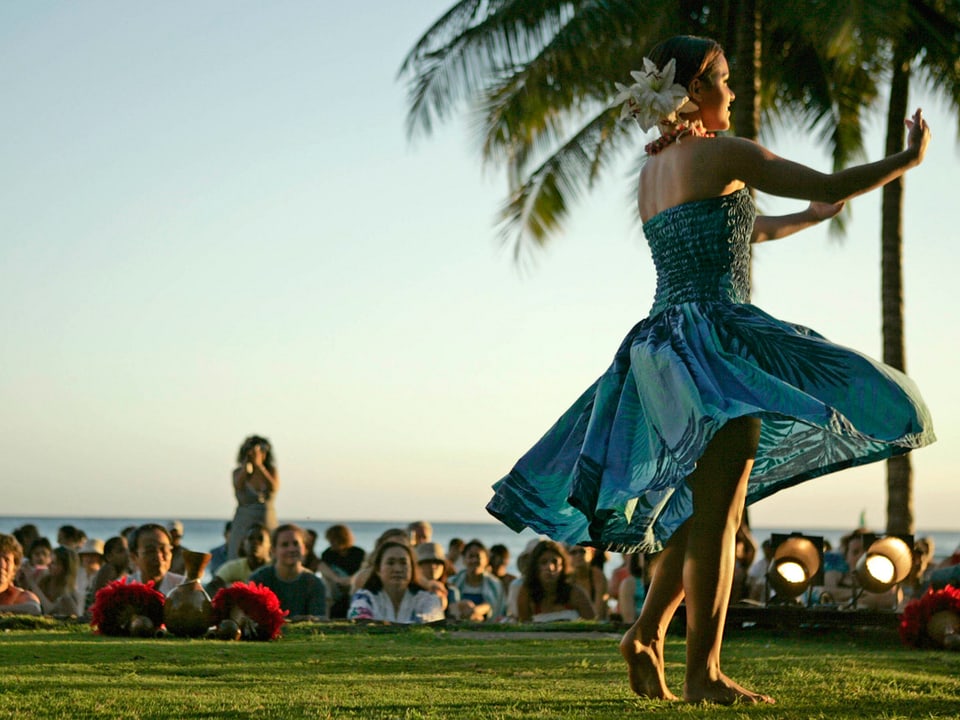 Eine Hula-Tänzerin auf Hawaii, bebobachtet von einem grossen Publikum.