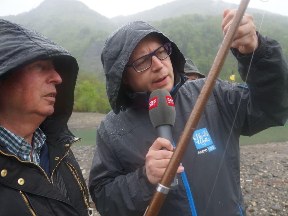 Zwei Männer mit Regenjacken und Angelrute.