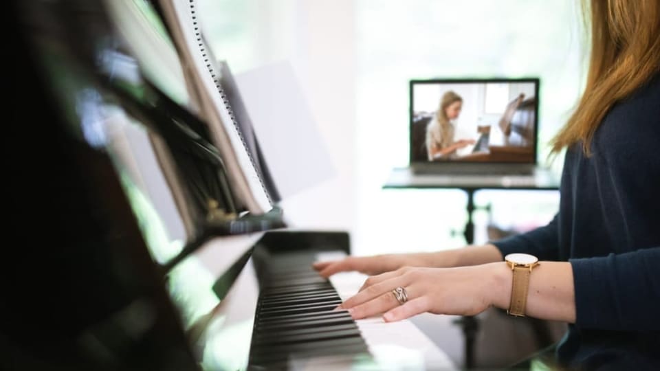 Frau am Klavier mit Bildschirm im Hintergrund