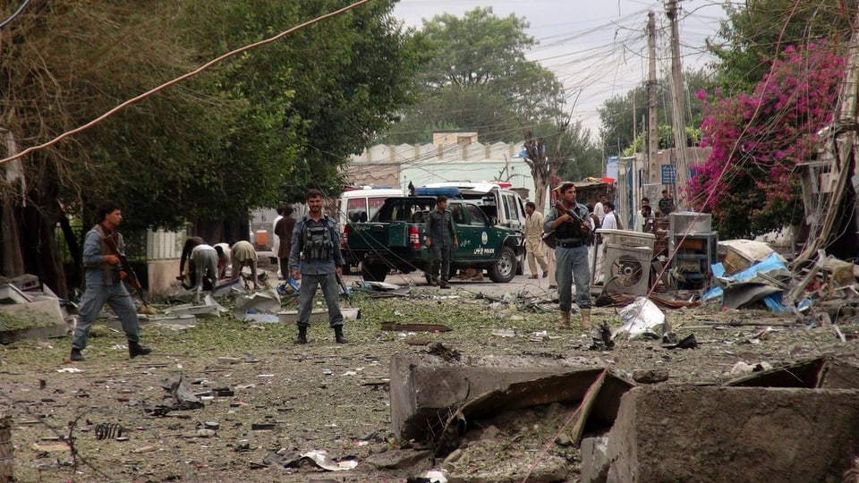 Drei bewaffnete Sicherheitskräfte vor den zerstörten Gebäuden.