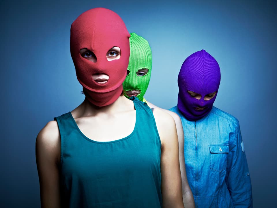 Drei Frauen mit farbigen Mützen über dem Gesicht.