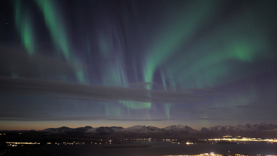 Polarlicht und Wolken über einer Stadt