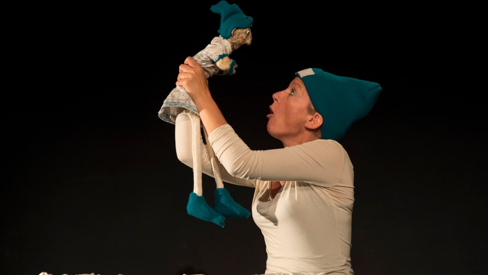 Eine Puppenspielerin hält eine Figur in die Höhe.