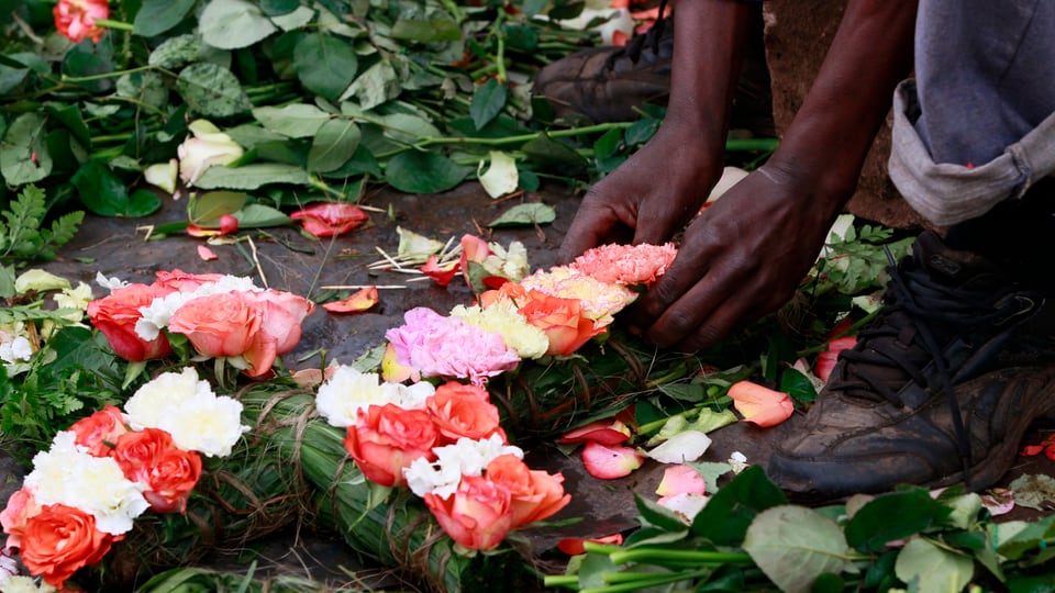Ein Kenianer legt ein Blumenkreuz zum Gedenken an die Opfer nieder.