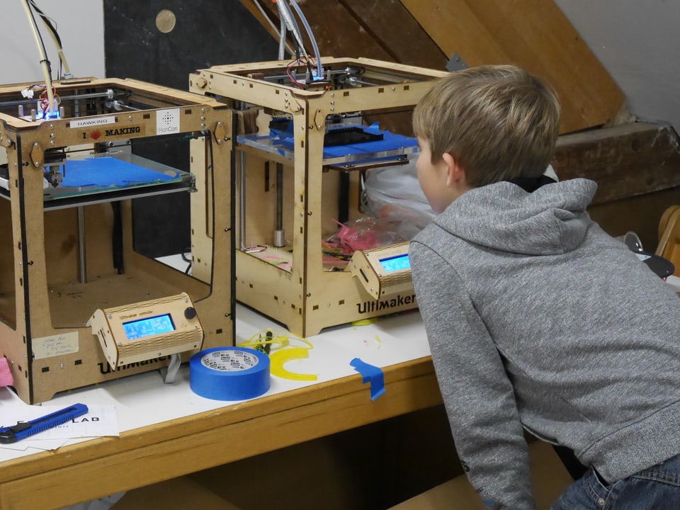 Ein Junge schaut fasziniert zu, wie ein 3D-Drucker ein PC-Gehäuse druckt.