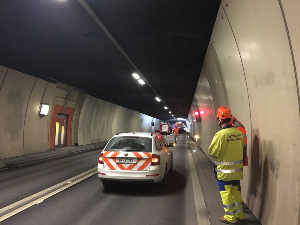 Ein Polizeiauto im Tunnel, dahinter Feuerwehrleute