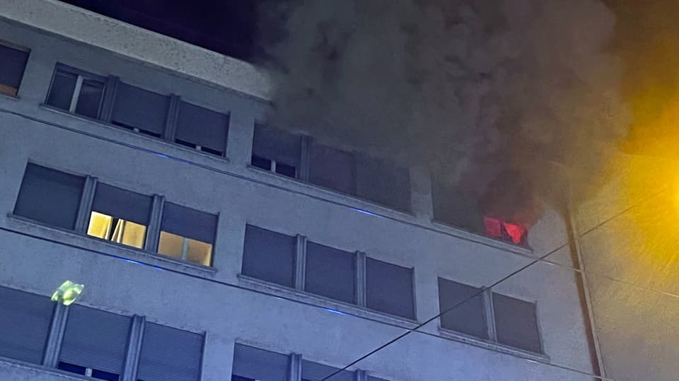 Aus einem Fenster im obersten Stock des Hauses brennt ein Feuer und steigt Rauch auf.