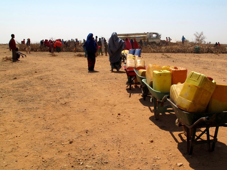 In einer Reihe aufgestellte Kanister, mit denen meist die Frauen das Wasser in ihr Dorf tragen.