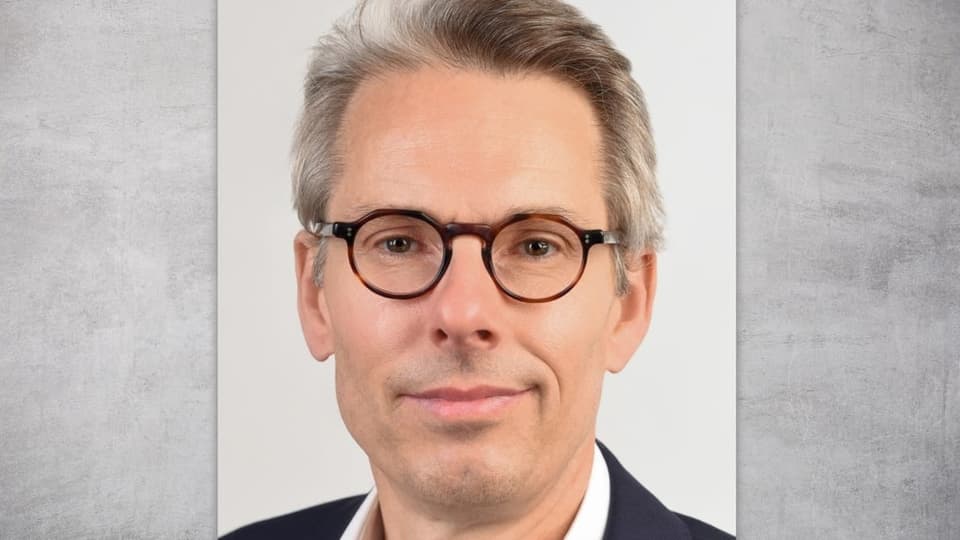 Fotoportrait von einem Mann mit grauen, kurzen Haaren und einer Brille.