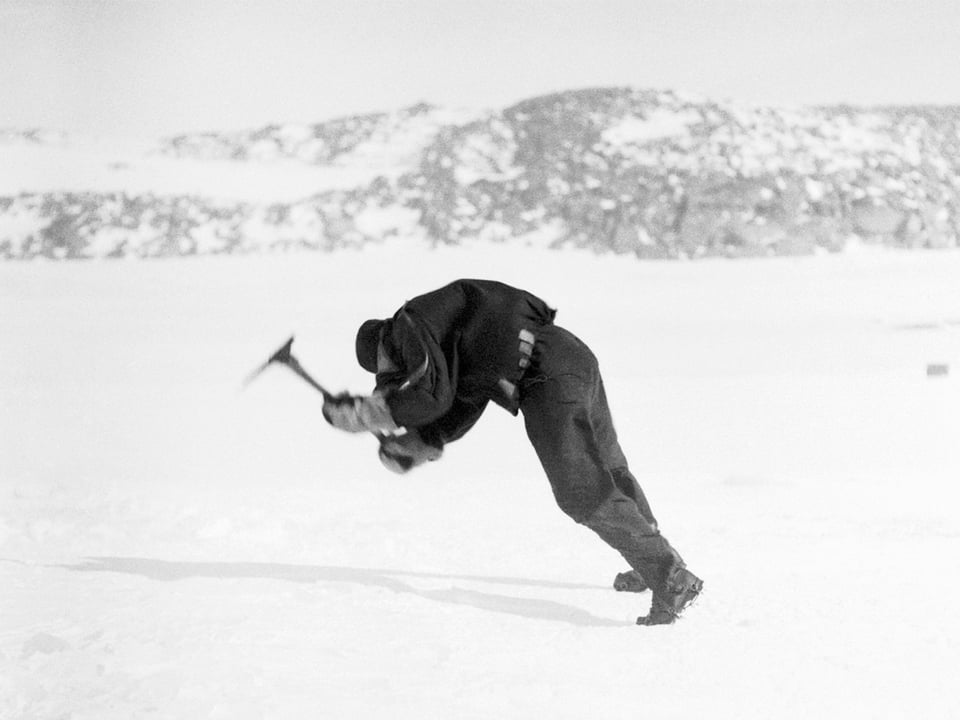 Ein Mann schlägt mit einem Bickel ins Eis.