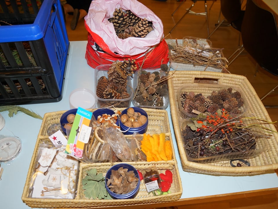Verschiedene Gegenstände zum Basteln in Körben und Schalen auf einem Tisch.